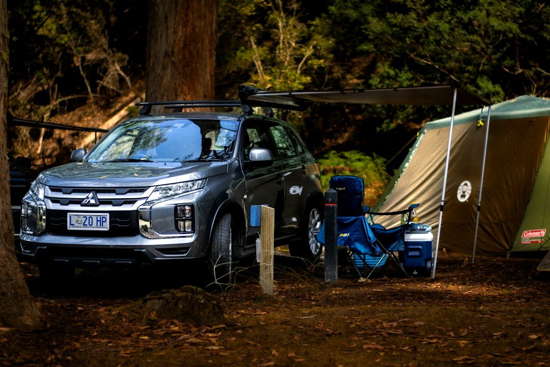 a-car-parked-next-to-a-tent-in-the-woods-o9arusep4f8